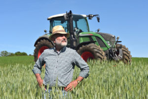 Agriculteur fier dans un champ avec un tracteur en arrière plan